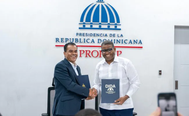 República Dominicana.-La Dirección General de Proyectos Estratégicos y Especiales de la Presidencia (Propeep) y la Dirección General de Información y Defensa de los Afiliados a la Seguridad Social (DIDA) firmaron este jueves 25 de junio de 2026, en la sede de Propeep, un acuerdo marco de colaboración interinstitucional con el propósito de fortalecer la orientación, educación, promoción y defensa de los derechos de la población en materia de seguridad social e inclusión social. El convenio fue suscrito por los directores generales de ambas instituciones, Robert Darío Polanco Tejada, de Propeep, y Elías Báez de los Santos, de la DIDA, quienes coincidieron en destacar la importancia de unir esfuerzos para acercar los servicios del Estado a las comunidades más vulnerables y garantizar que los ciudadanos conozcan y ejerzan plenamente sus derechos dentro del Sistema Dominicano de Seguridad Social. Mediante esta alianza, ambas entidades desarrollarán acciones conjuntas de orientación, capacitación, acompañamiento y defensoría, dirigidas especialmente a personas en condiciones de vulnerabilidad, con el objetivo de facilitar su acceso a los beneficios y prestaciones contemplados en la Ley 87-01 que crea el Sistema Dominicano de Seguridad Social. Durante el acto, el director general de Propeep, Robert Polanco, afirmó que el acuerdo fortalece el compromiso del Gobierno del presidente Luis Abinader de llevar soluciones concretas a las comunidades más necesitadas mediante una gestión cercana, humana e inclusiva. “Este acuerdo permitirá que miles de ciudadanos que participan en nuestras jornadas de inclusión social y programas comunitarios reciban información oportuna, orientación especializada y acompañamiento para acceder a servicios fundamentales de salud, protección social y pensiones solidarias", expresó Polanco. Al referirse al convenio, el director general de la DIDA, Elías Báez, destacó que la firma representa un paso trascendental para ampliar el alcance institucional y multiplicar su impacto. "Esta alianza nos permitirá integrar capacidades, fortalecer la presencia territorial del Estado y llegar a más comunidades con orientación, educación y servicios que contribuyan a mejorar la calidad de vida de nuestra gente", afirmó. El acuerdo contempla la realización de jornadas comunitarias de información y asesoría, talleres, conferencias, diplomados y actividades educativas dirigidas a líderes comunitarios, organizaciones sociales, estudiantes y ciudadanía en general, así como la participación conjunta en operativos sociales y programas territoriales. Asimismo, establece el desarrollo de acciones de defensoría administrativa individual y colectiva para asistir a afiliados que enfrenten dificultades en el acceso a servicios y prestaciones del sistema, y promueve el acceso al régimen subsidiado del Seguro Familiar de Salud, los programas de protección social y las pensiones solidarias destinadas a adultos mayores en condición de vulnerabilidad. Para garantizar la ejecución efectiva de las iniciativas contempladas en el convenio, ambas instituciones conformarán una comisión gestora encargada de coordinar, supervisar y dar seguimiento a los programas y actividades que se desarrollen en el marco de la colaboración. La firma de este acuerdo reafirma el compromiso de Propeep y la DIDA con la construcción de una sociedad más inclusiva, equitativa y solidaria, mediante el fortalecimiento de las políticas públicas orientadas a mejorar la calidad de vida de la población y ampliar el acceso efectivo a los derechos sociales.